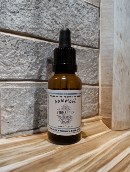 Amber glass dropper bottle of Vibrasens Bach flowers sleep elixir on wooden surface with stone tile background